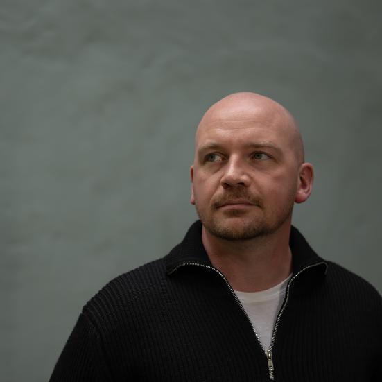 Morten Pape med mørk grå-grøn baggrund, han ser mod venstre