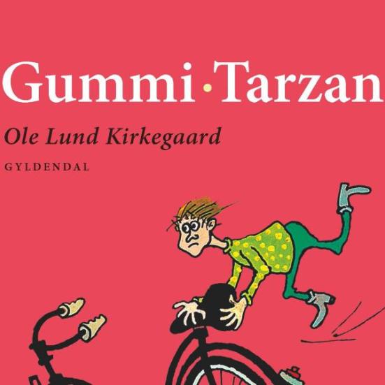 Det øverste af en ældre udgave af en Gummi-Tarzan bog. Baggrunden er rød, og man kan se den stakkels Gummi-Tarzan holde fast i sadlen på en cykel, mens den suser afsted