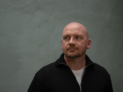 Morten Pape med mørk grå-grøn baggrund, han ser mod venstre